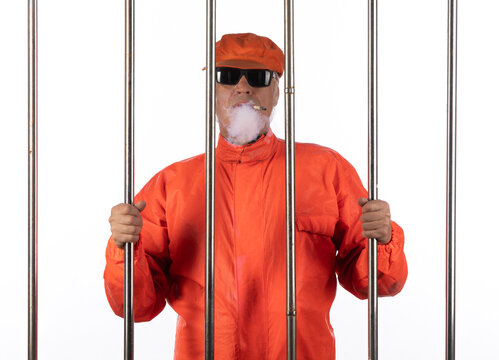 male prisoner smoking a cigarette behind bars