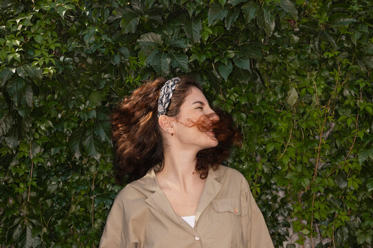 Young woman spinning head while standing against plants
