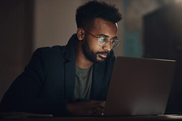 Business, man and reading laptop at night for checking stock market review, financial investment and serious. Professional, trader and glasses with problem solving for NFT trading and inflation news