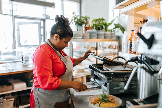 Female chef using toaster while preparing food in kitchen at restaurant