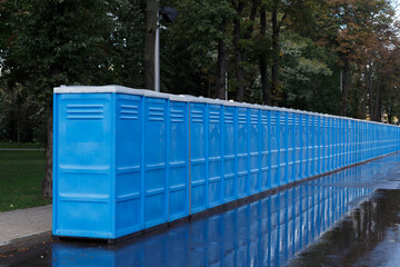 Row of blue toilets outside in the summer.