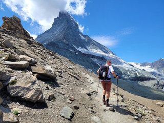 Wandern am Matterhorn in den schweizer Alpen - Wanderer läuft in Richtung Matterhorn auf einem Steig den Berg hoch