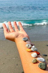 Girl holding stones on hand at the beach

