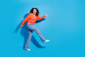 Photo portrait of young latin funny lady with curly hairstyle in orange cardigan dancing silent going like cat isolated on blue color background