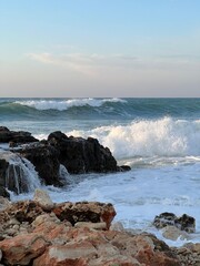 Waves crashing against rocky shore under a calm evening sky