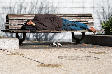 Un homme sans domicile fixe qui dort sur un banc public