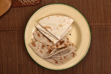 South east Asian Indian Pakistan Bangladesh staple Wheat flower flatbread chapati tandoori roti on rustic metal tin plate brown mat background