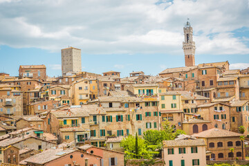 Fototapeta premium Scenic view of historic italian town, a picturesque shot of an italian town with rustic buildings, charming architecture, and a tall clock tower under a cloudy sky