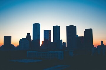 Fototapeta premium Silhouette of skyscrapers against a sunset sky, showcasing urban architecture.