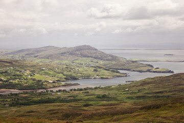 Overlooking a picturesque valley in County Donegal, Ireland, with green pastures, small villages, and calm coastal waters. The image is captured with a vintage style, emphasizing the rustic charm