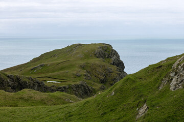 The cliffs curve like a wave against the seamless backdrop of ocean merging with the sky, creating...