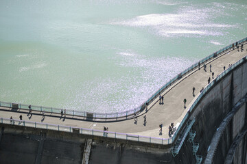 Kurobe Dam, Tateyama, Toyama, Chubu, Japan A scenic view of a dam with people walking along its curved path
