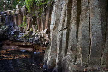 Close-up view of striking basalt rocks near a waterfall, featuring unique hexagonal patterns formed...
