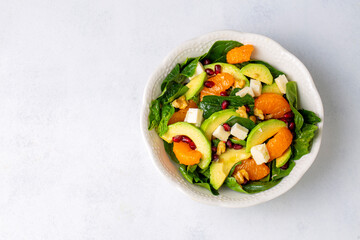 Close up view of spinach, avocado salad with orange, pomegranate and walnut