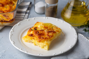 Potato gratin - graten (baked potatoes with cream and cheese) with rosemary and forks (Turkish name; Kremali patates)