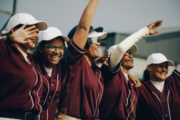 Excited women's baseball team with arms raised in team spirit