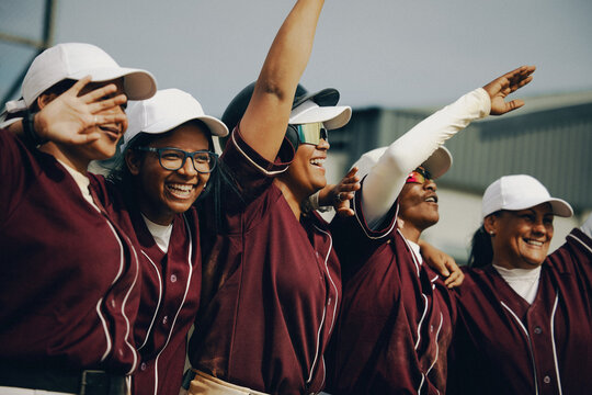 Excited women's baseball team with arms raised in team spirit - Powered by Adobe