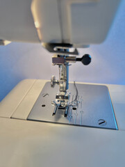 Modern sewing machine presser foot with linen fabric and thread, closeup, copy space. Sewing process clothes, curtains, upholstery. Business, hobby, handmade, zero waste, recycling, repair concept