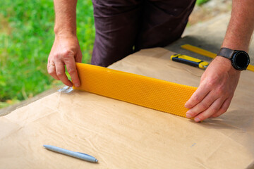 Man cuts beeswax blank for the production of decorative candles