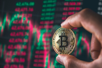 Bitcoin Blockchain Technology and Cryptocurrency. Hand holding bitcoin with graph background for Digital Finance and trading concept.