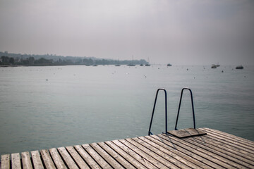 Calm Dock Overlooking Serene Misty Water with Boats