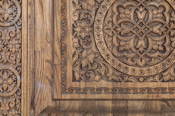 Fragment of an ancient carved wooden door. Ornate background.