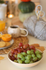 Pumpkins, various food and drinks, fall decorations, books and candles on the table. Fall hygge at home. Selective focus.