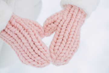 Close-up of a woman in pink mittens outdoors in a city park in winter.