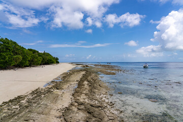 Shallow Rocky Water and Sandy Beach looking south with boats on beautiful tropical Mataking Island (Pulau Mataking), Semporna, Sabah, Malaysia (Borneo)