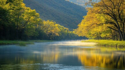 Misty morning river with golden leaves and mountains in the background.