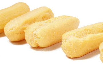 Neatly stacked mini cream puffs (sus kering) in a thumb-sized, golden-yellow shape. Photographed on a white background. Perfect as a light snack.