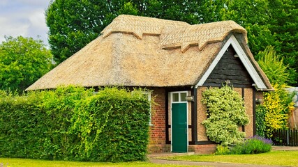 Fototapeta premium a quaint thatched-roof cottage surrounded by lush greenery. The cottage features traditional craftsmanship, with natural materials and a charming, rustic architectural style.