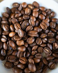 Close-up of roasted coffee beans in a white bowl, showcasing rich brown tones and textures