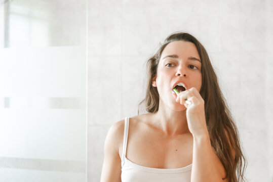Young woman brushing teeth in a bright bathroom