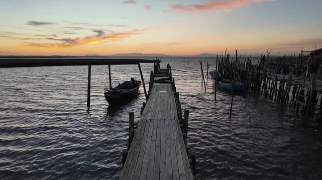 Porto Palafitico in Comporta, Portugal, featuring traditional wooden stilts and rustic fishing boats along the winding pier, capturing the charm of this unique harbor on a calm 