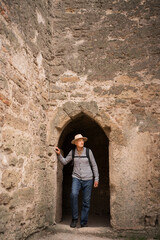 Retired male tourist gazes from arch within the brick walls of an ancient fortress standing near space for text