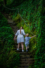 Woman and child climbing stone steps in dark forest