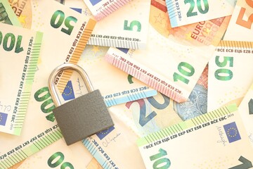 Euro banknotes with lock on wooden table background