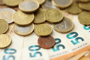 Many cent coins of euro currency lies on many fifty euro bills banknotes