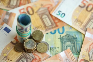 Roll of euro currency money bills and many euro cents on banknotes of european union