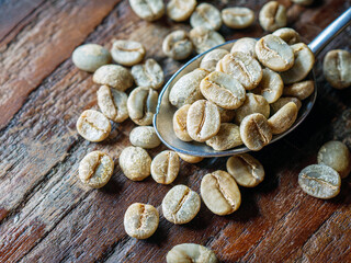 Top view green coffee bean on a stainless steel spoon, Close-up of fresh raw coffee bean, unroasted  coffee bean on wooden table, macro