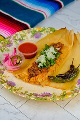 Mexican beef tacos with jalapenos, parsley, sauce and pickles on a floral plate on a tiled floor