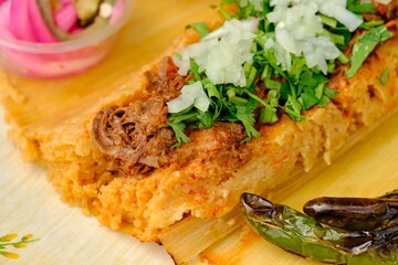 beef filling with onions and greens prepared for a taco, with fried peppers and pickles around it