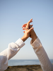 Two women joyfully raise their clasped hands towards the clear blue sky, showcasing a moment of...