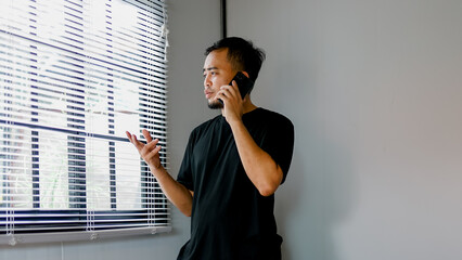 Cheerful young businessman talking on mobile phone in the office.
