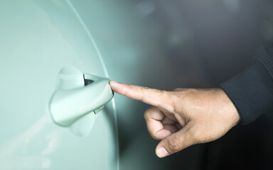 A man's hand touching the car door to unlock it without using a remote or key. Represents the...