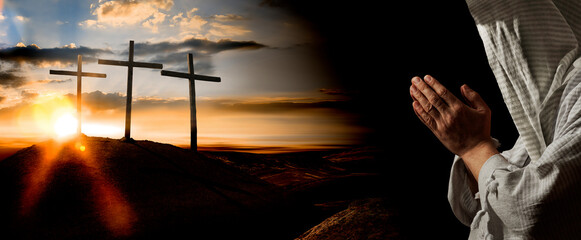 A praying man and three wooden crosses on hill against sky. Biblical Crucifixion on Mount Golgotha,...