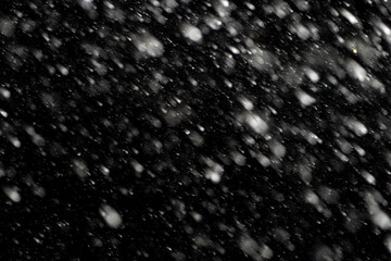 Bokeh effect of snowfall and lights. Abstract blurred background with snowflake in the night sky, White spots and dots in the dark. Snowy stormy weather, falling snow