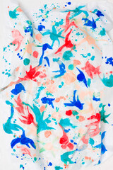Abstract painted figures of different colors, on a white sheet of paper, in the artist's studio. Background for your design or addition to creative illustrations.
