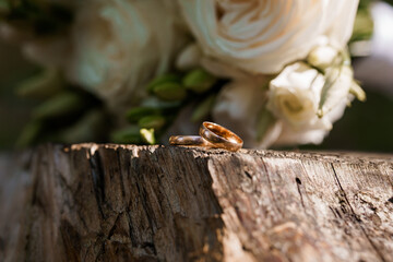 Wedding Rings on a Rustic Wooden Surface with Floral Backdrop
